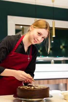 Bäckerin verziert einen Schokoladenkuchen