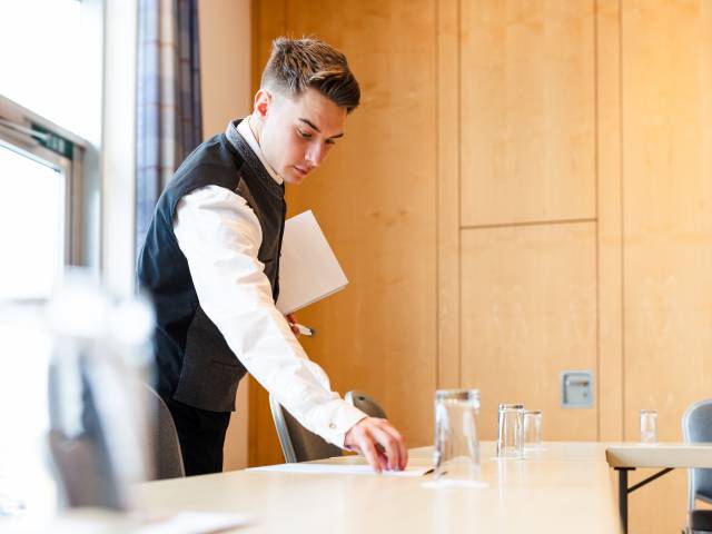 Service Mitarbeiter deckt Tagungsraum ein