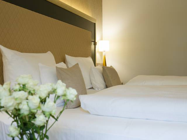 frisch gemachtes Doppelbett mit Blumenstrauß